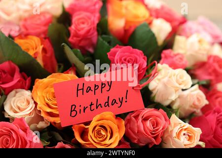 Bouquet of beautiful roses with Happy Birthday card, closeup Stock Photo