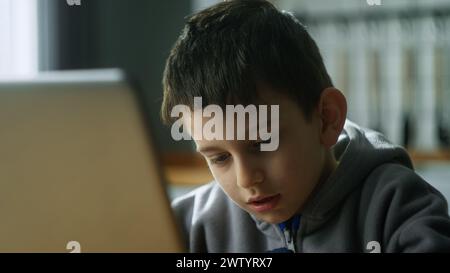 Close-up of boy typing on laptop keyboard. Kid using computer for distance education online. Learning computer device technology Stock Photo
