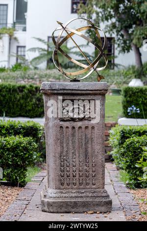 Brass or bronze large scale armillary sundial sphere with raised roman numerals and arrow directional on plinth, stone pedestal with pattern. Hotel ba Stock Photo