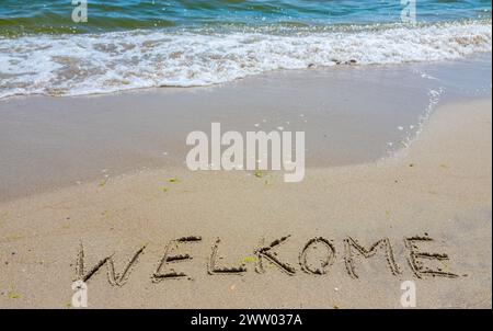 Handwritting inscription welkome word on tropical sandy beach, travel concept card for holidays. Stock Photo