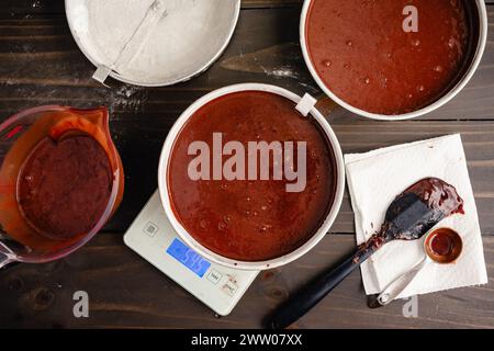 Weighing Cake Pans Filled with Chocolate Batter: Round floured cake pans being weighed with a digital kitchen scale for even distribution and size Stock Photo