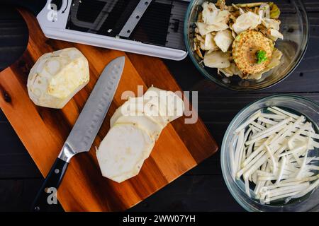 Peeled, Sliced, and Julienned Celery Root: Thin slices of celeriac on a wooden cutting board to be cut into matchsticks for celery root remoulade Stock Photo