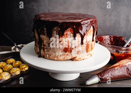 Chocolate Cake with Hazelnut Frosting Covered in Chocolate Ganache: Layer cake on a cake stand with dark chocolate glaze dripping down the sides Stock Photo