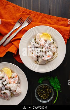 Poached Seafood Salad Served on Celery Root Remoulade: Bowls of shrimp, squid, and scallops with lemon dill sauce served over celeriac remoulade Stock Photo