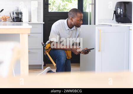 African American plumber fixing sink while using tablet Stock Photo