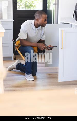 African American plumber fixing sink while using tablet Stock Photo