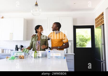 A diverse couple doing recycling together in the kitchen at home Stock Photo