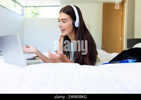 A young Caucasian brunette woman is on a video call while studying with a laptop Stock Photo