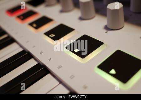 Detail of a modern mini synthesizer with red, orange and yellow glowing buttons. Stock Photo