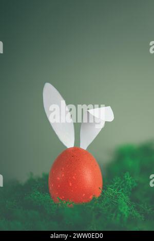 easter brown egg with white rabbit ears among green moss. creative minimalistic easter photo with copy space Stock Photo