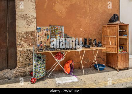 Cartagena, Colombia - July 25, 2023: Street vendor display on flimsy wooden foldable table and rolling chest of small souvenir statues and other tiny Stock Photo