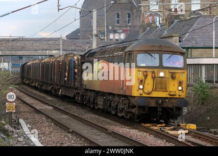 Colas Rail freight class 56 gridiron diesel-electric loco, 56113, passing through Carnforth on the West Coast Main Line with log train 20 March 2024. Stock Photo