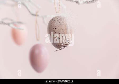 Tree branch decorated with Easter eggs on pastel pink background Stock Photo