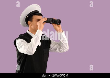 Young sailor looking through binoculars on lilac background Stock Photo