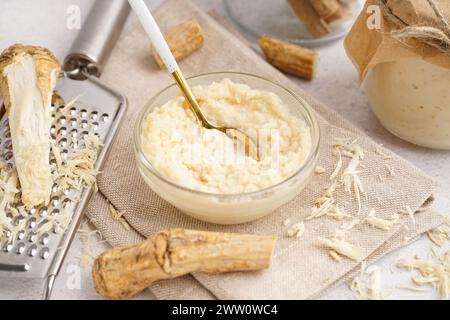 Bowl of horseradish sauce with horseradish roots on white background Stock Photo