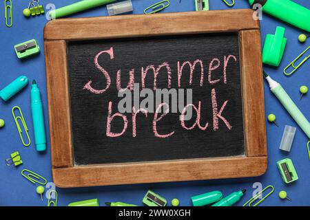 Blackboard with text SUMMER BREAK and different stationery on blue background. Closeup Stock Photo