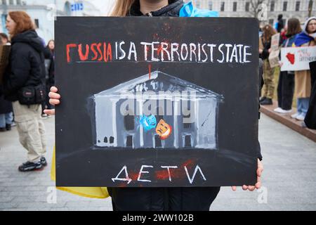 Ukrainian activist shows a banner with Mariupol Drama Theatre and a writing 'russia is a terrorist state' on a demonstration dedicated to russian airstrike in 2022. Kyiv - 17 March,2024 Stock Photo