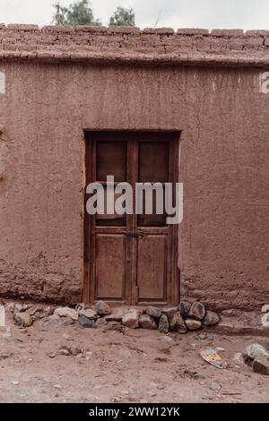 Weathered wooden door set in a rustic earthen wall in Tilcara, Jujuy Province, Argentina. Stock Photo