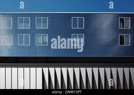 Modern architecture with its clean lines, reflective glass windows, and symmetrical design. The alternating pattern of windows on the dark blue facade Stock Photo