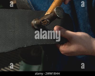 detail shot of a cobbler's hands working on a shoe with a hammer Stock Photo