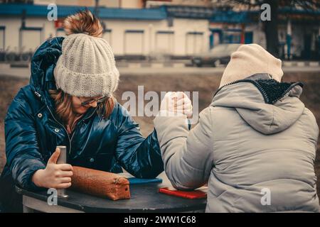 two girls arm wrestle in the park Stock Photo