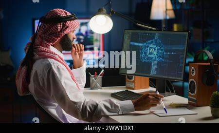 Man in home office typing on keyboard, updating artificial intelligence neural networks, writing complex binary code scripts. Muslim freelancer in personal office upgrading high tech AI Stock Photo