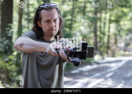 Content creator using. a phone gimbal to film in nature with a blurred forest in the background Stock Photo