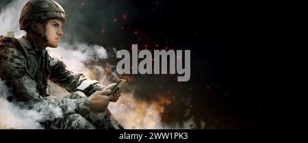 Armed soldier using tablet in smoke on black background, space for text. Banner design Stock Photo