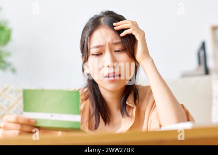A woman holding a bank note while looking at it Stock Photo