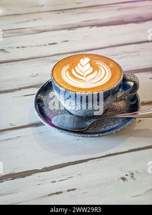Flat White coffee in a blue cup on top of wood table. Copy space. Stock Photo