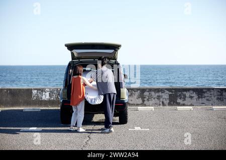 A man and woman standing next to a car with the trunk open Stock Photo
