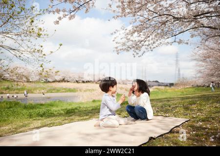 Two children sitting on a blanket in the park Stock Photo
