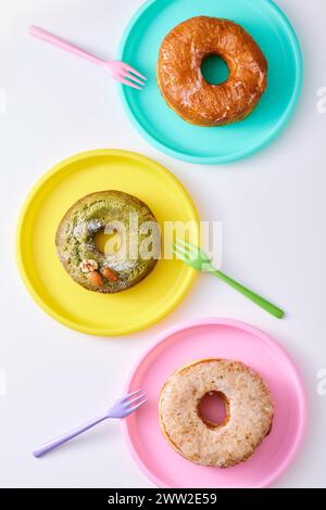 Three donuts on colorful plates with forks Stock Photo