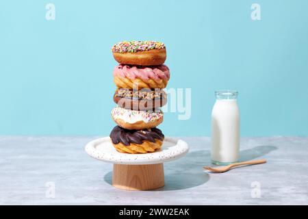 A stack of donuts on a wooden stand next to a glass of milk Stock Photo