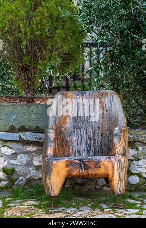 Old wooden dark and brown chair, with metal rusty leggings in the yard of monastery Saint Naum of Ohrid. Throne seat, concept. Macedonia 2024. Stock Photo