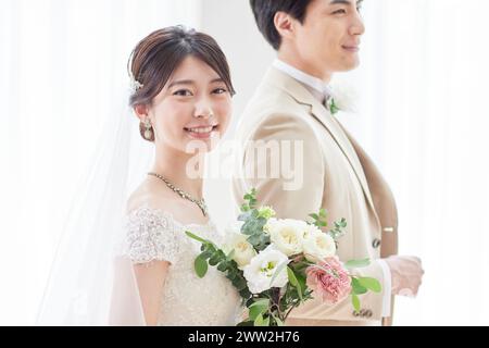 A bride and groom standing in front of a window Stock Photo