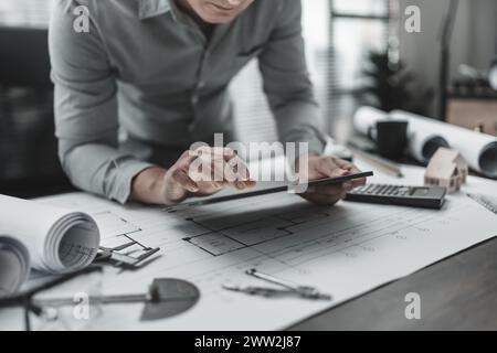 Architect, Engineering working with house drawings inspection on tablet in the office. Engineer, Architect, Industry and factory concept. Stock Photo