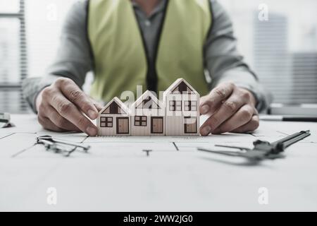 Architect, engineer show house model repersent design or sell house on blueprint. Architect and engineer concept. Stock Photo