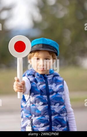 Child, boy, holding start/stop policeman control traffic paddle, wanting to become a policeman in the future Stock Photo