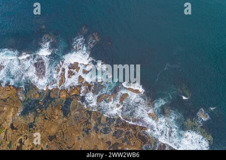 Overhead drone view captured by drone of ocean waves crashing on a rocky shore Stock Photo