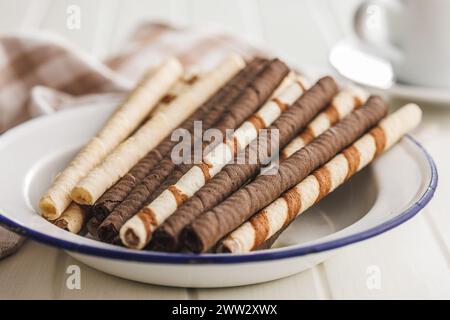 Assorted Chocolate and Vanilla Cream Filled Wafer rolls on plate on a white table. Stock Photo
