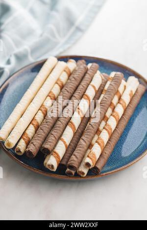 Assorted Chocolate and Vanilla Cream Filled Wafer rolls on plate on a white table. Stock Photo