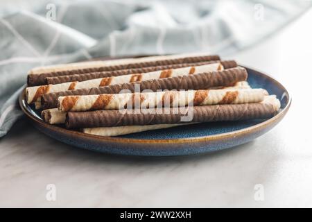 Assorted Chocolate and Vanilla Cream Filled Wafer rolls on plate on a white table. Stock Photo