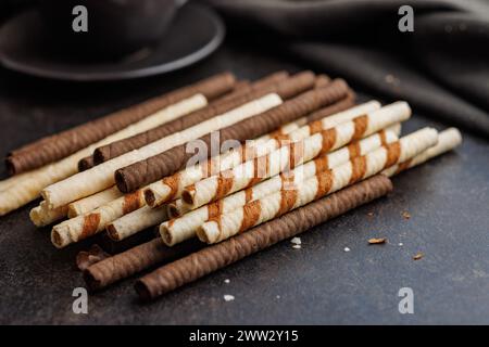 Assorted Chocolate and Vanilla Cream Filled Wafer rolls on a dark table. Stock Photo