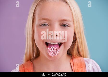Child, portrait and tongue out in studio for crazy, silly and playful facial expression with color block background. Happy, goofy and funny face of Stock Photo