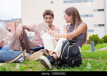 Two college students sitting together on campus lawn reviewing exam Stock Photo