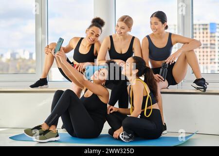 group of five and cheerful multicultural women in sportswear taking selfie after yoga class Stock Photo
