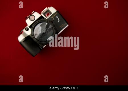 A high-resolution image featuring a vintage camera positioned flat against a solid red surface Stock Photo