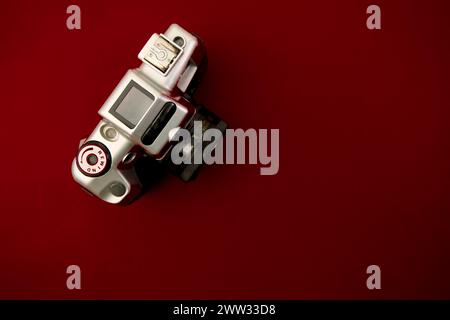 A high-resolution image featuring a vintage camera positioned flat against a solid red surface Stock Photo