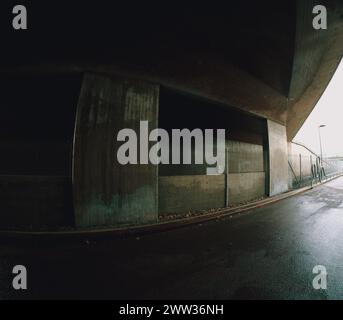 Empty urban underpass in rough concrete and wet asphalt a rainy day. Stock Photo